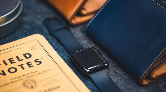 Apple Watch with Black Silicone Watch Strap next to notebook and wallet