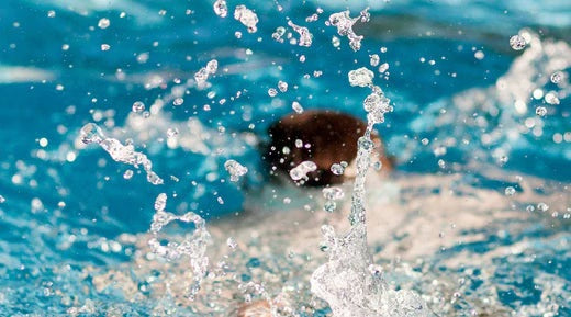 Man swimming in swimming pool water splashing around him